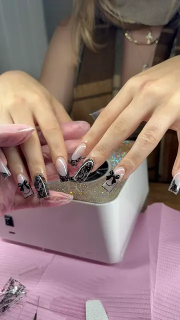 Long square nails with sheer nude base, black lace French tips and lace accent nails, finished with black 3D bows
